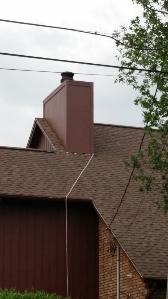A brown chimney is on the roof of a house.