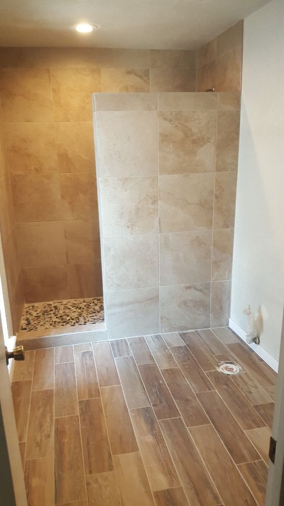 A bathroom with a walk in shower and wooden floors.