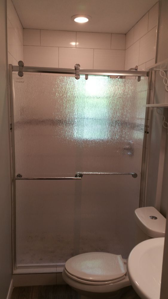 A bathroom with a toilet , sink and shower with a sliding glass door.