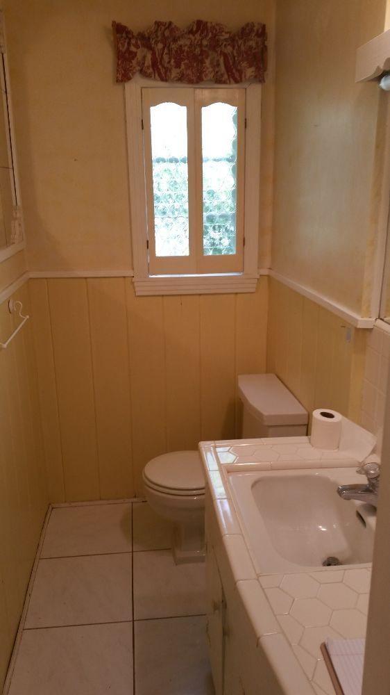 A bathroom with a toilet , sink , and window.