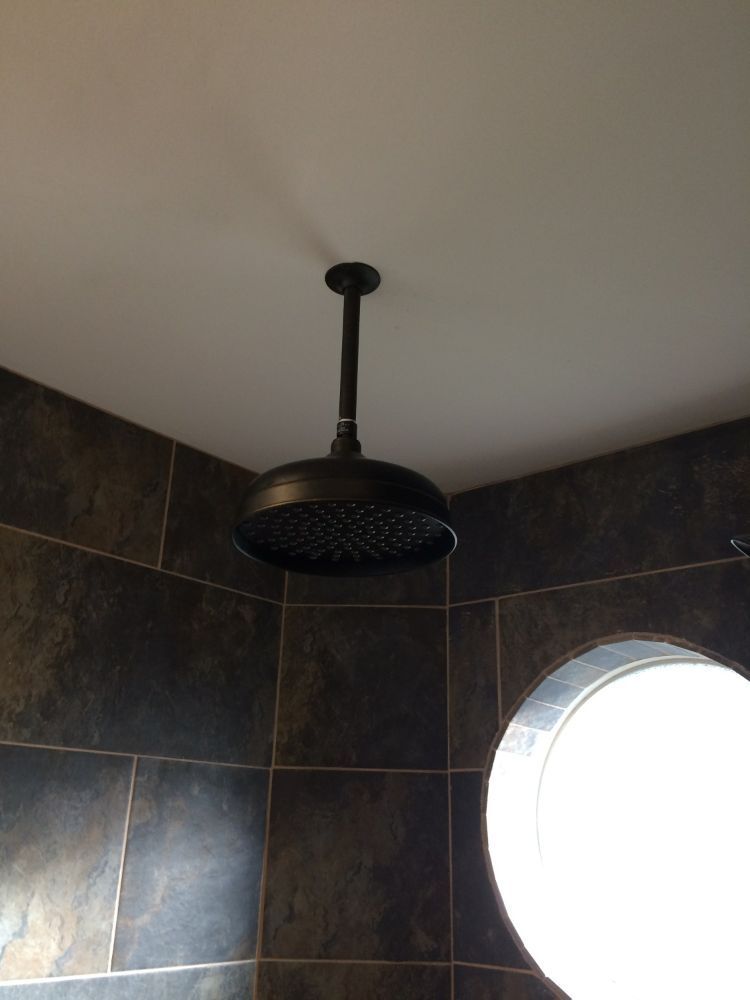 A shower head is hanging from the ceiling in a bathroom