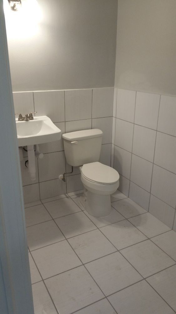 A bathroom with a toilet , sink and tile floor.