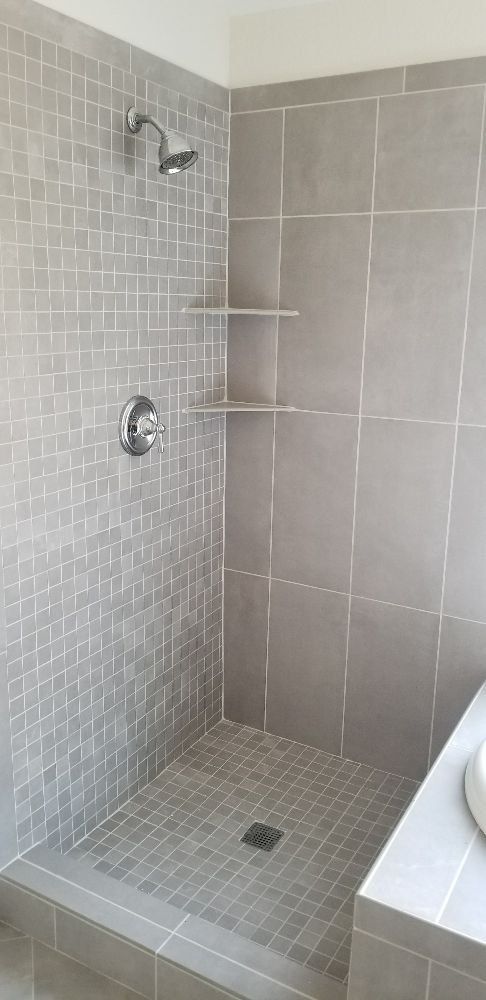A bathroom with a walk in shower and a sink.