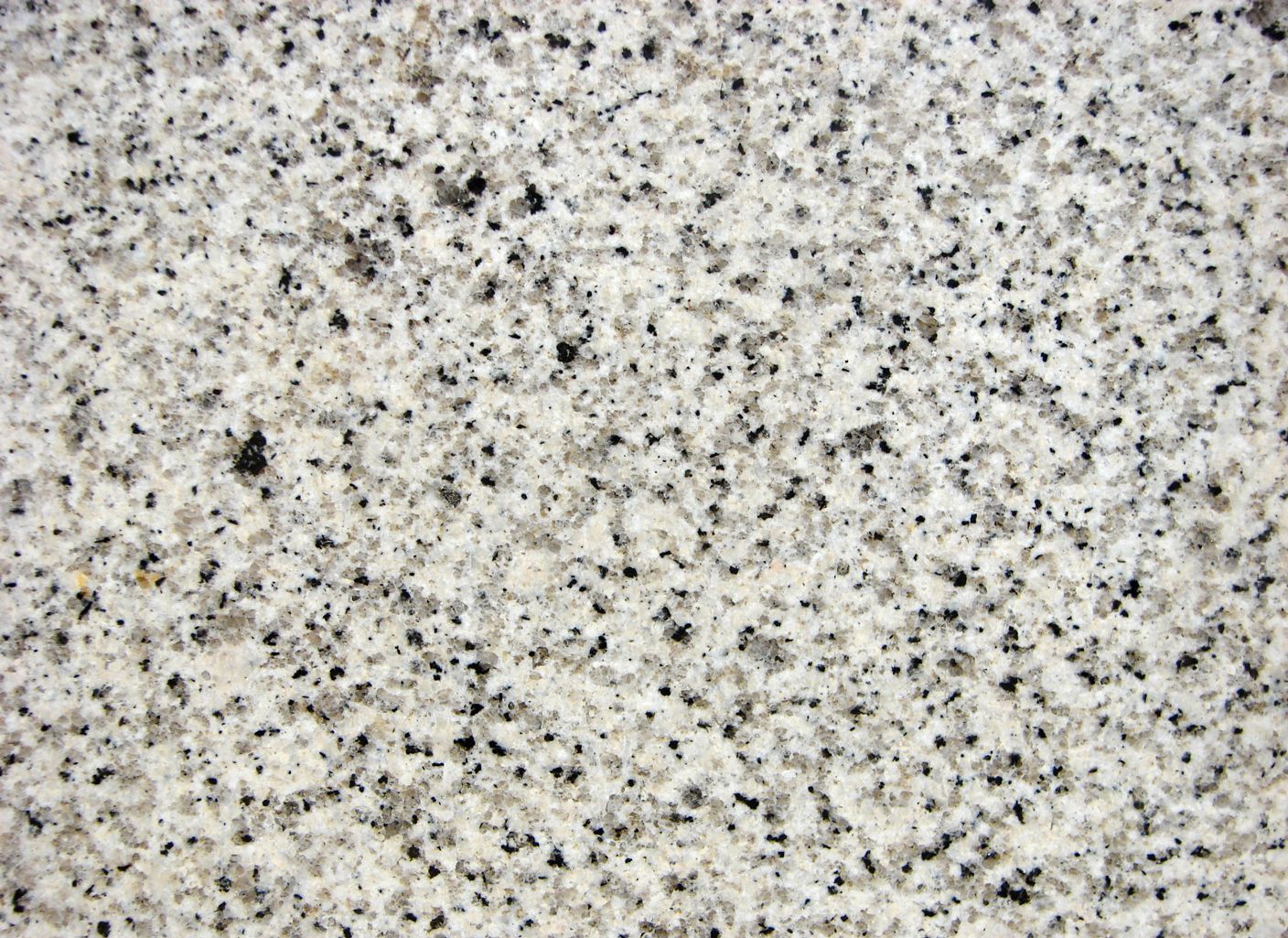 Un primer plano de una encimera de granito blanco con manchas negras
