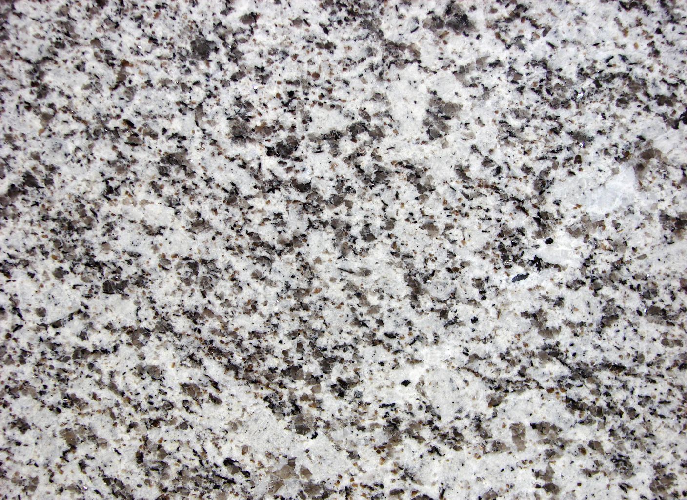 Un primer plano de una encimera de granito blanco con manchas negras