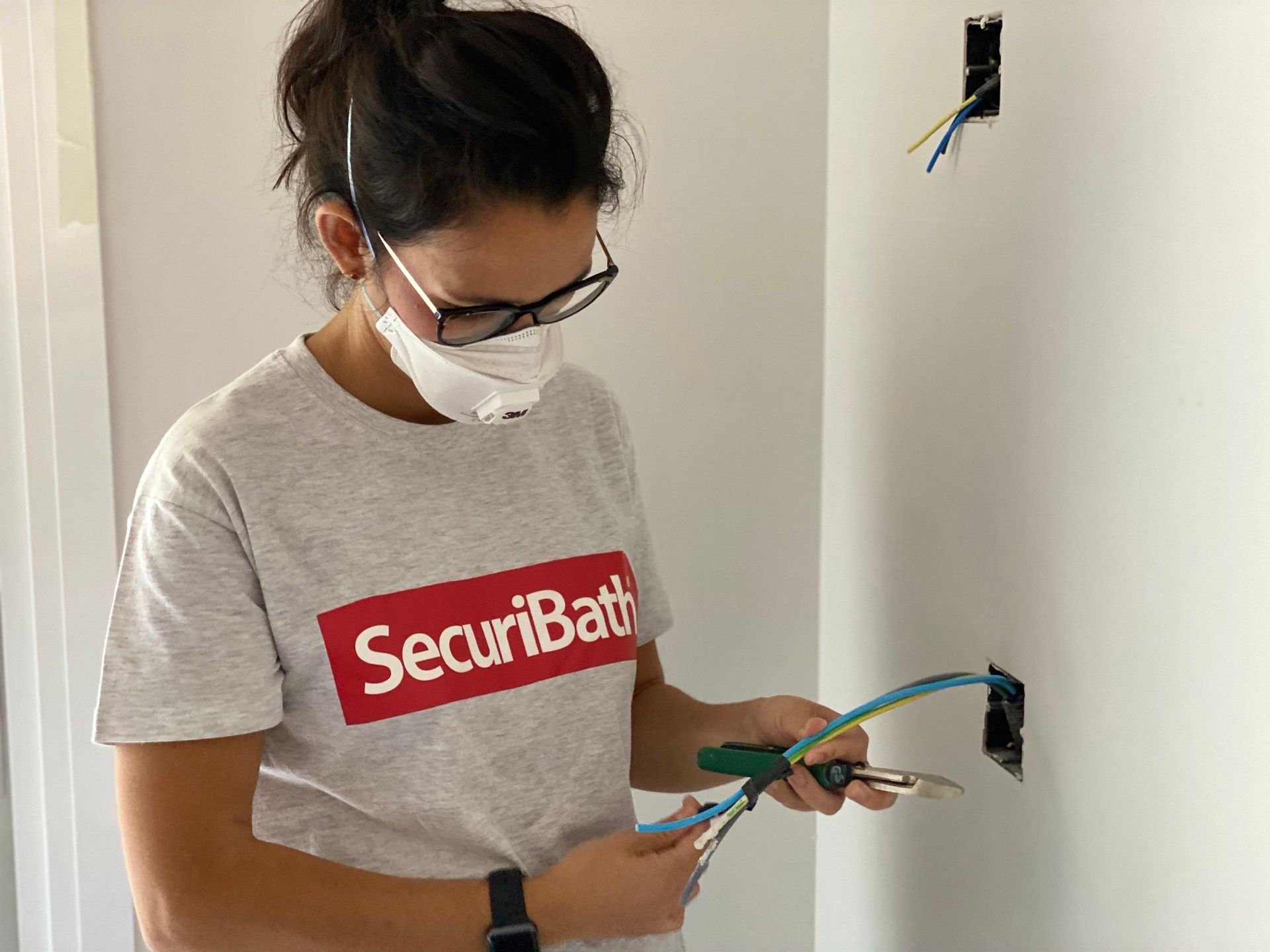 Una mujer con máscara y gafas está trabajando en una pared.