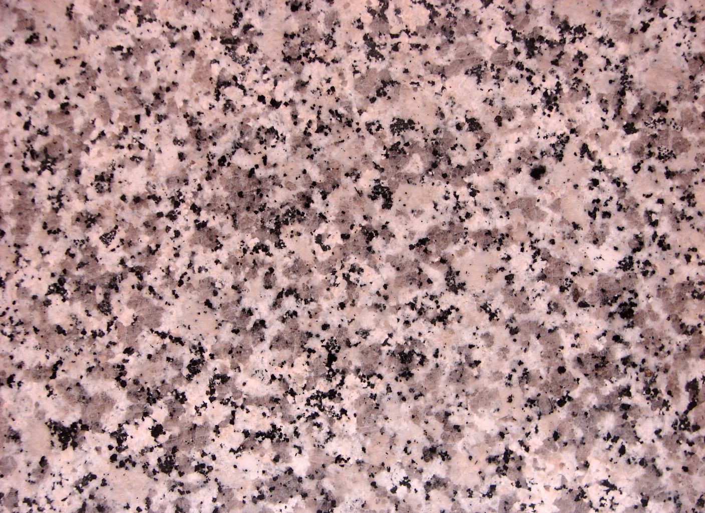 Un primer plano de una encimera de granito rosa con manchas negras