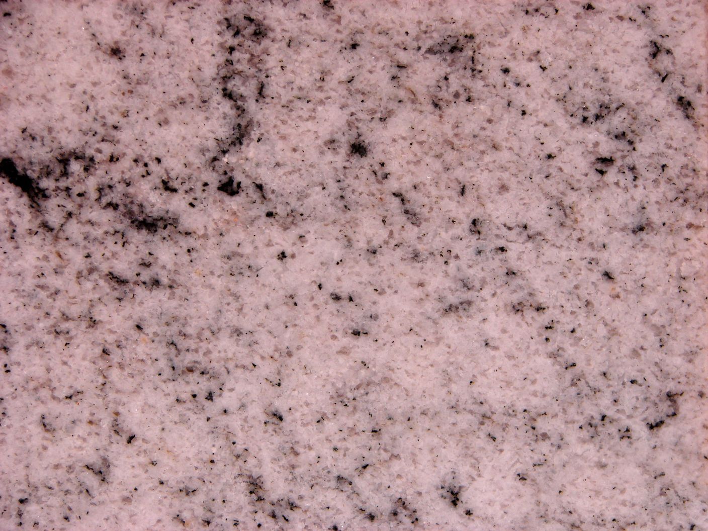 Un primer plano de una encimera de granito rosa con manchas negras