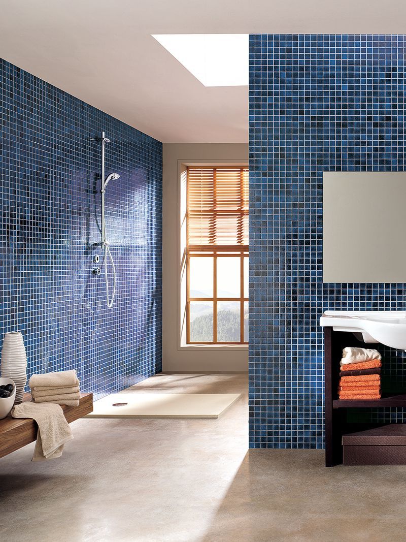 Un baño con azulejos azules y una ventana.