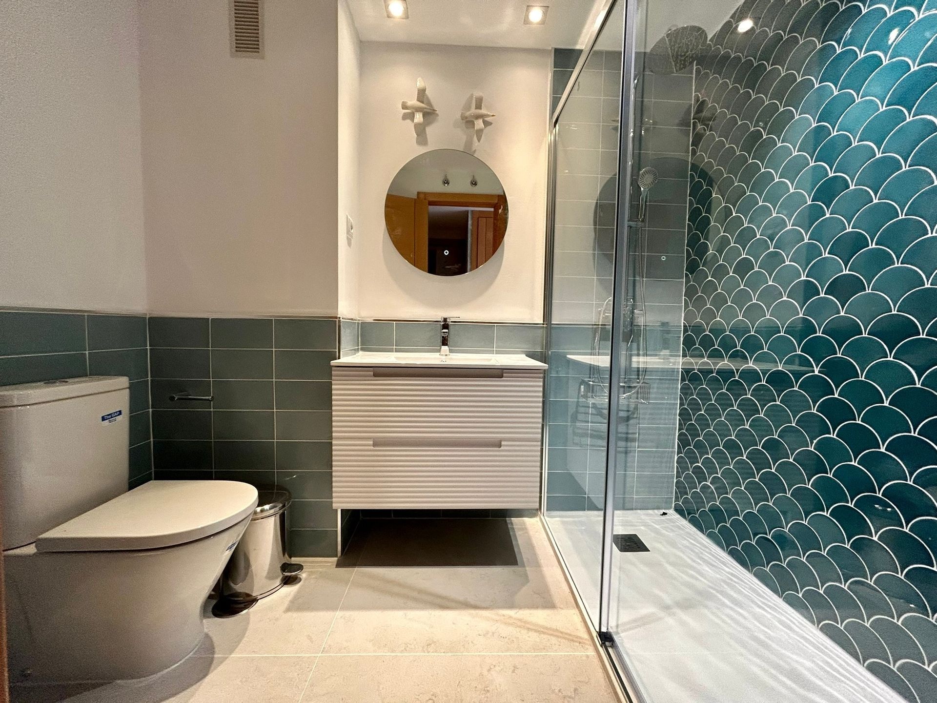 Un cuarto de baño con inodoro, lavabo, espejo y ducha.