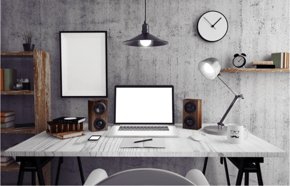 Un escritorio con una computadora portátil, parlantes, una lámpara y un reloj.