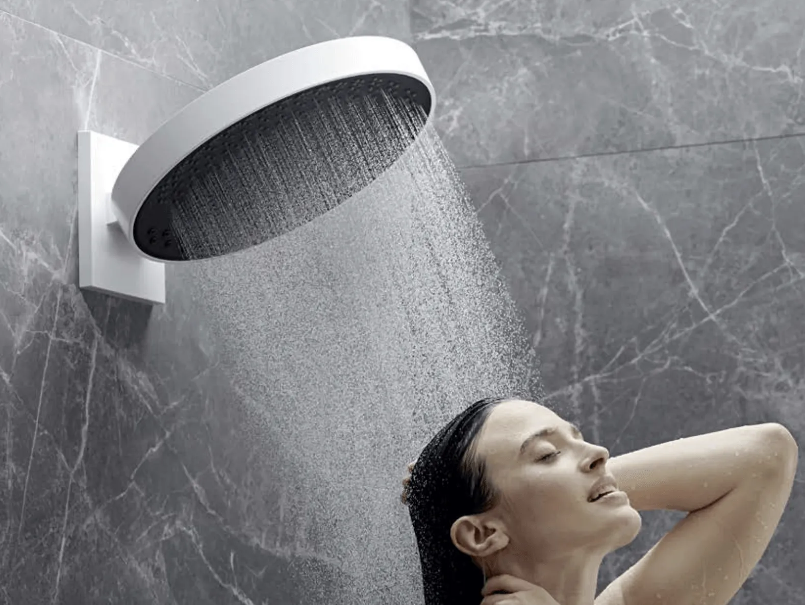 Una mujer se está duchando con un cabezal de ducha grande.