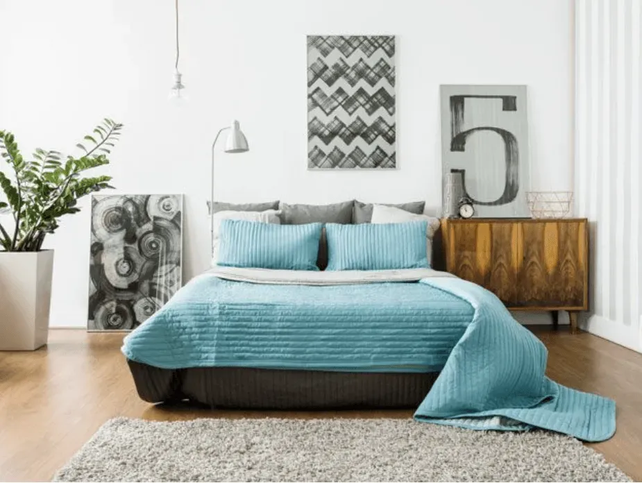 Un dormitorio con cama, cómoda, alfombra y cuadros en la pared.