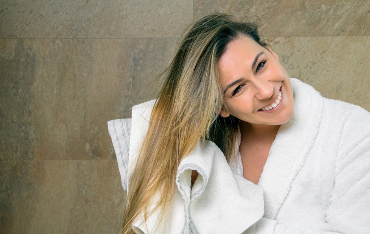 Una mujer en bata de baño se seca el cabello con una toalla.