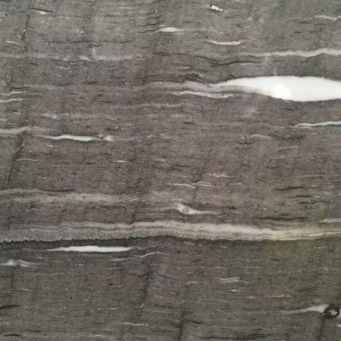 Un primer plano de un trozo de madera con textura de mármol gris y blanco.