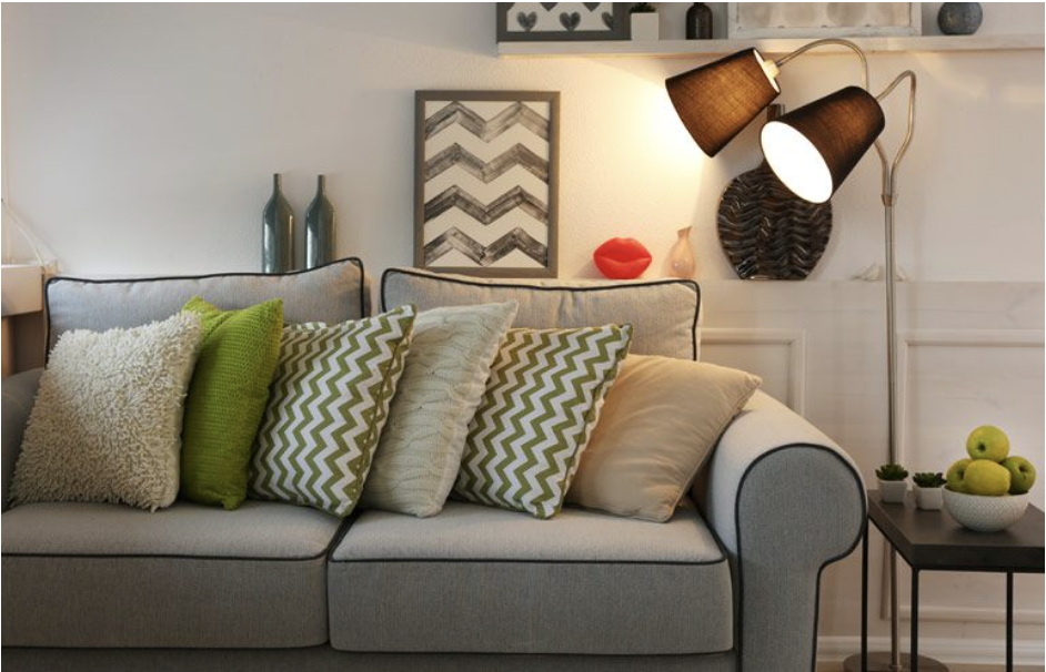 Una sala de estar con un sofá, almohadas y una lámpara.