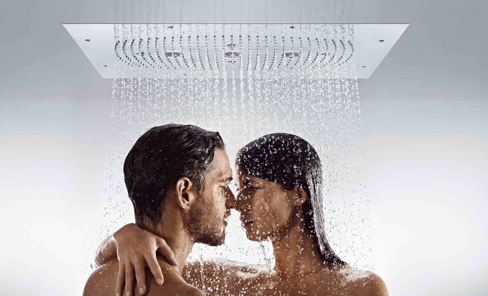 Un hombre y una mujer se besan en la ducha.