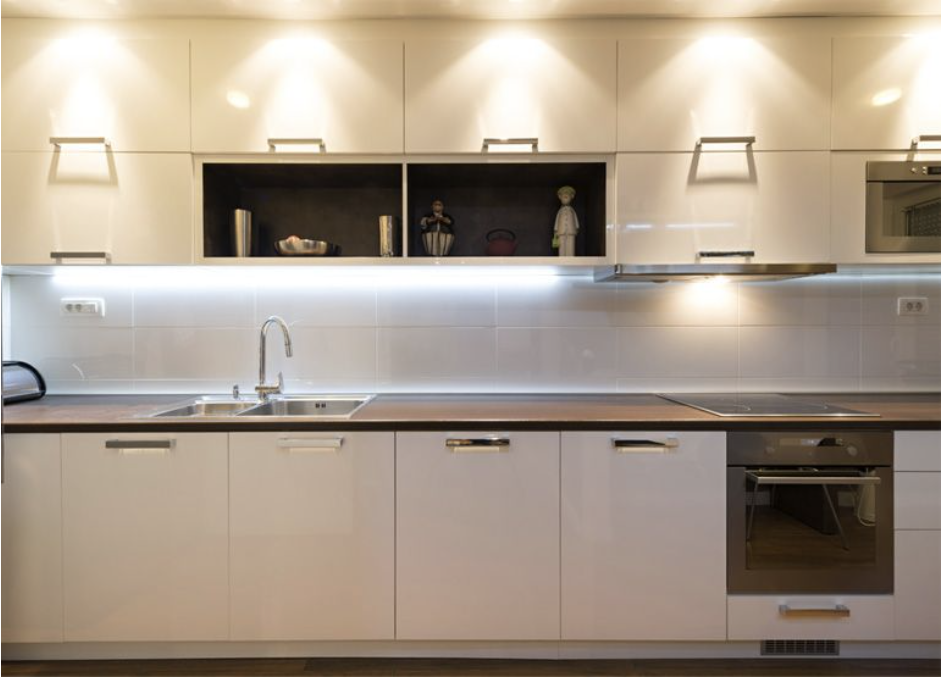 Una cocina con gabinetes blancos, fregadero y estufa.