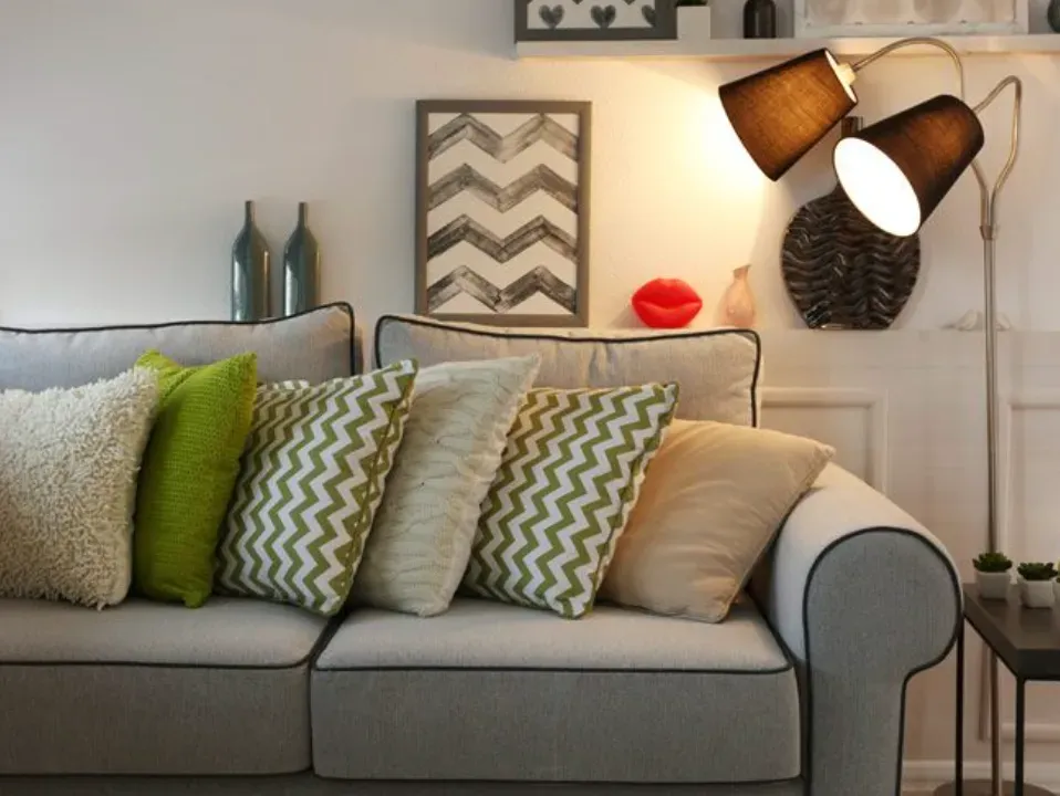 Una sala de estar con un sofá, almohadas y una lámpara.