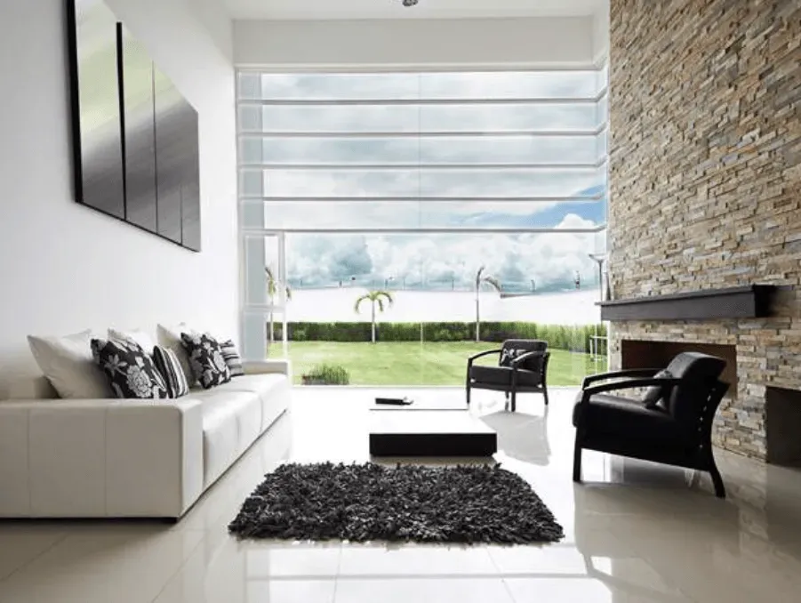 Un salón con un sofá blanco y sillas negras.