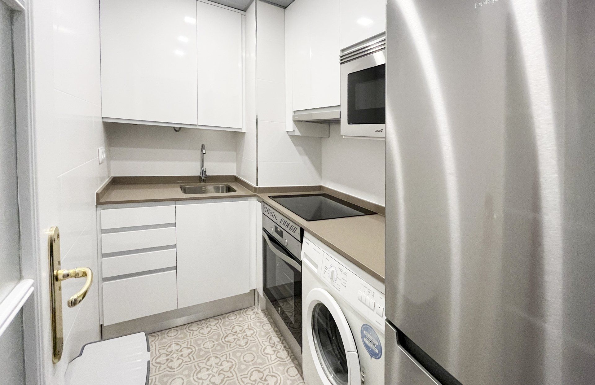 Una cocina con electrodomésticos de acero inoxidable y gabinetes blancos.