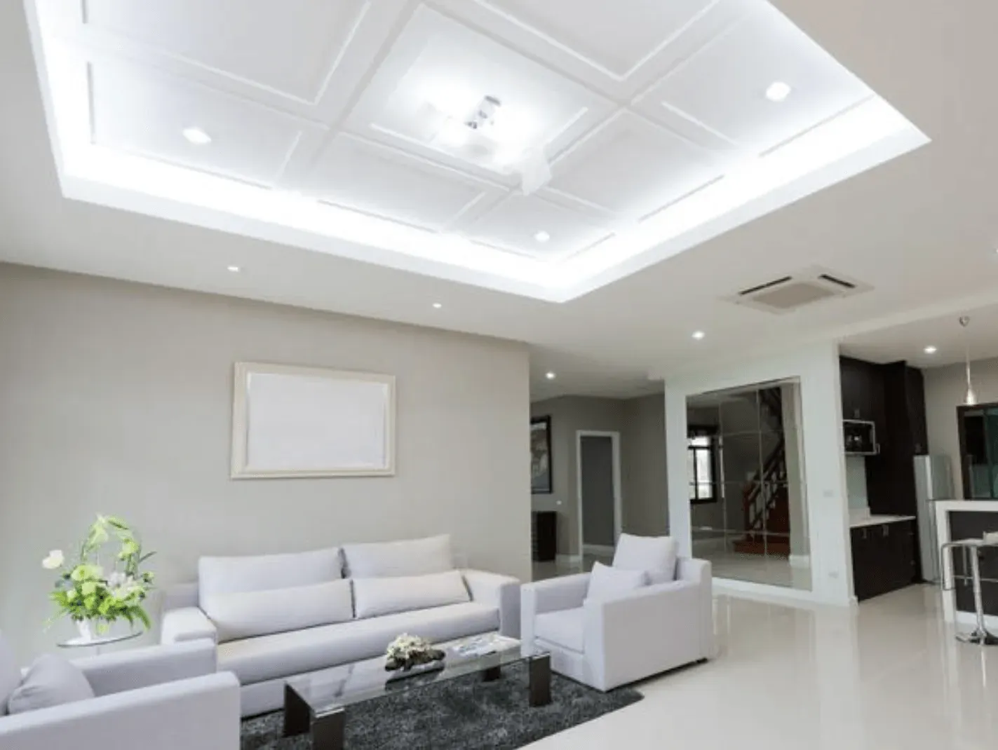 Una sala de estar con muebles blancos y ventilador de techo.