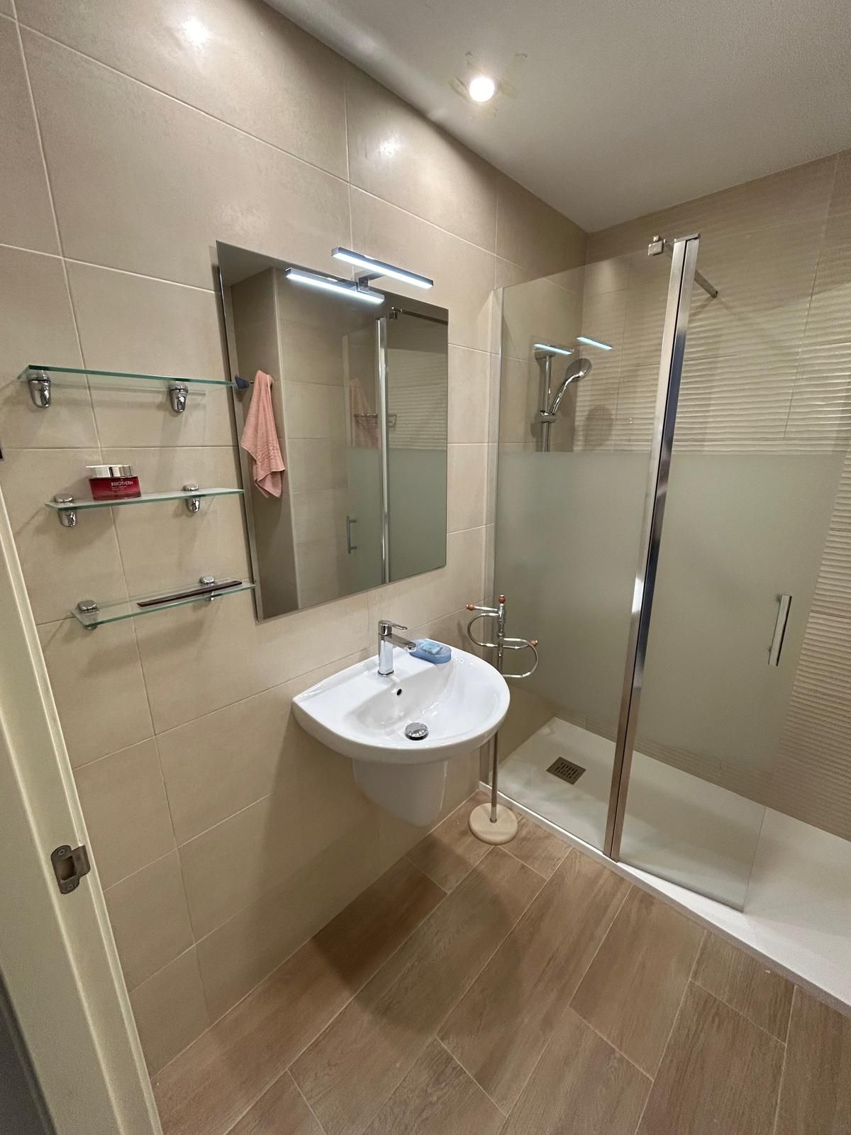 Un cuarto de baño con inodoro, lavabo, espejo y ducha.