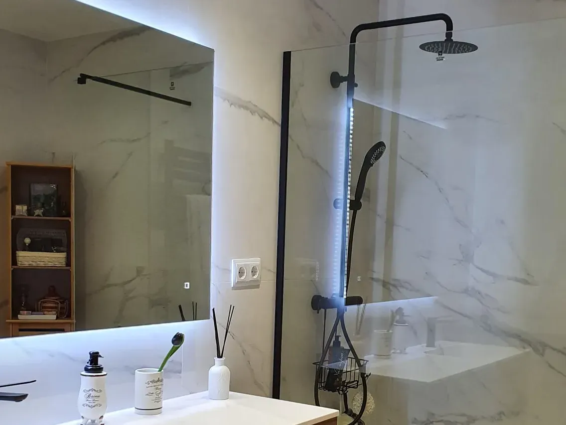 Un baño con lavabo, ducha y espejo.