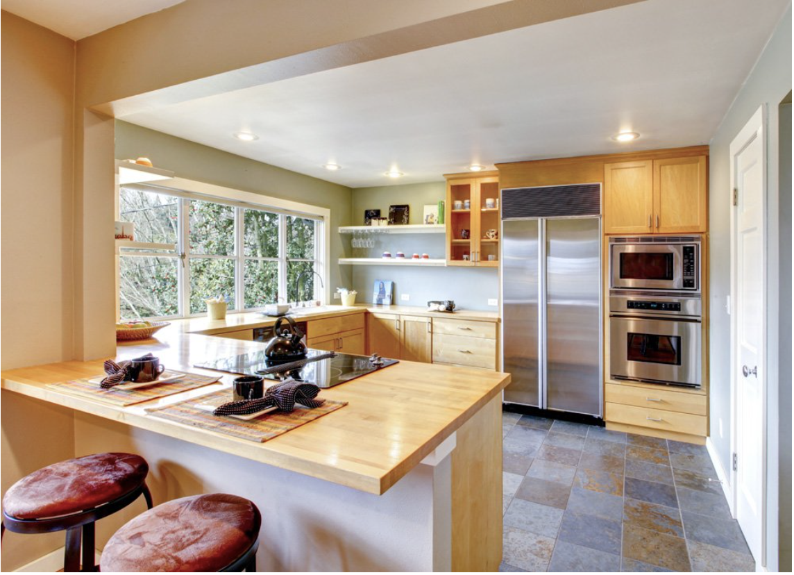 Una cocina con electrodomésticos de acero inoxidable y encimera de madera.
