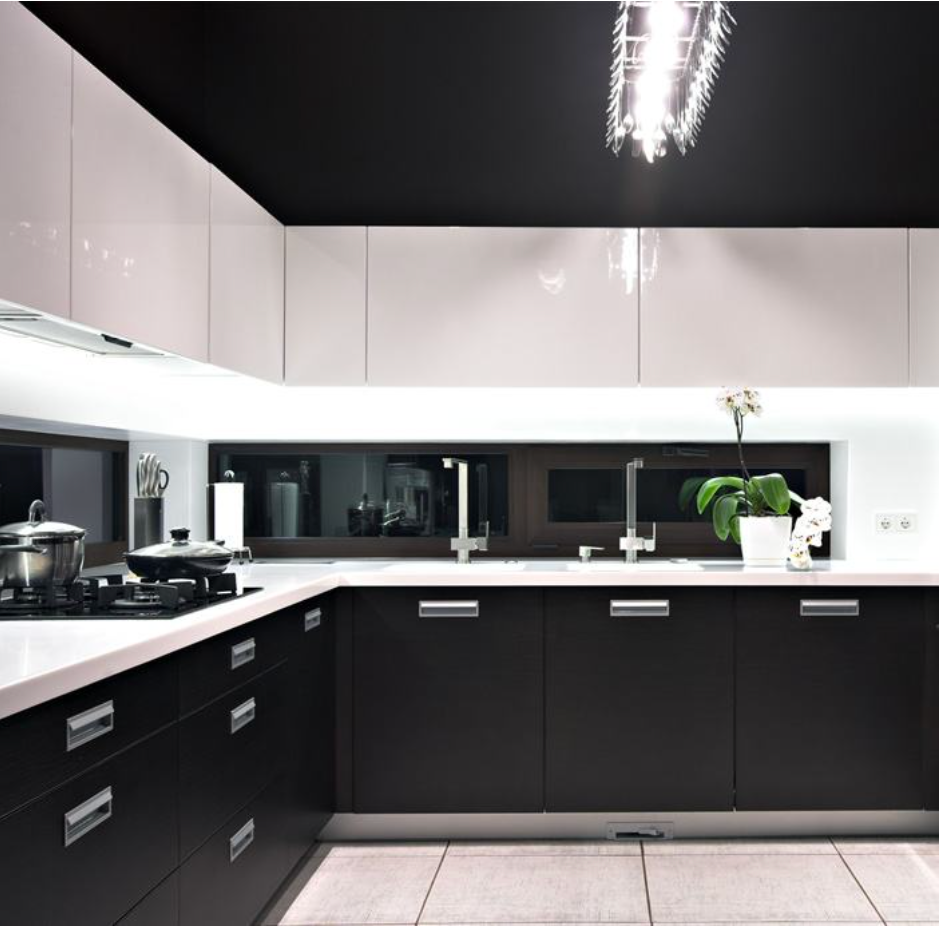 Una cocina con gabinetes negros y encimeras blancas.