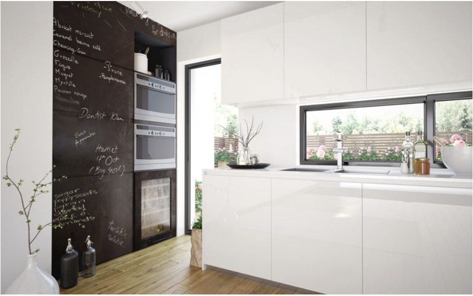 Una cocina con pared de pizarra y gabinetes blancos.