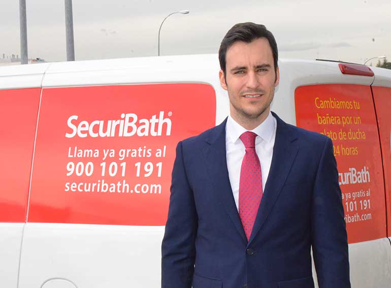 Un hombre con traje y corbata se encuentra frente a una camioneta de seguridad.