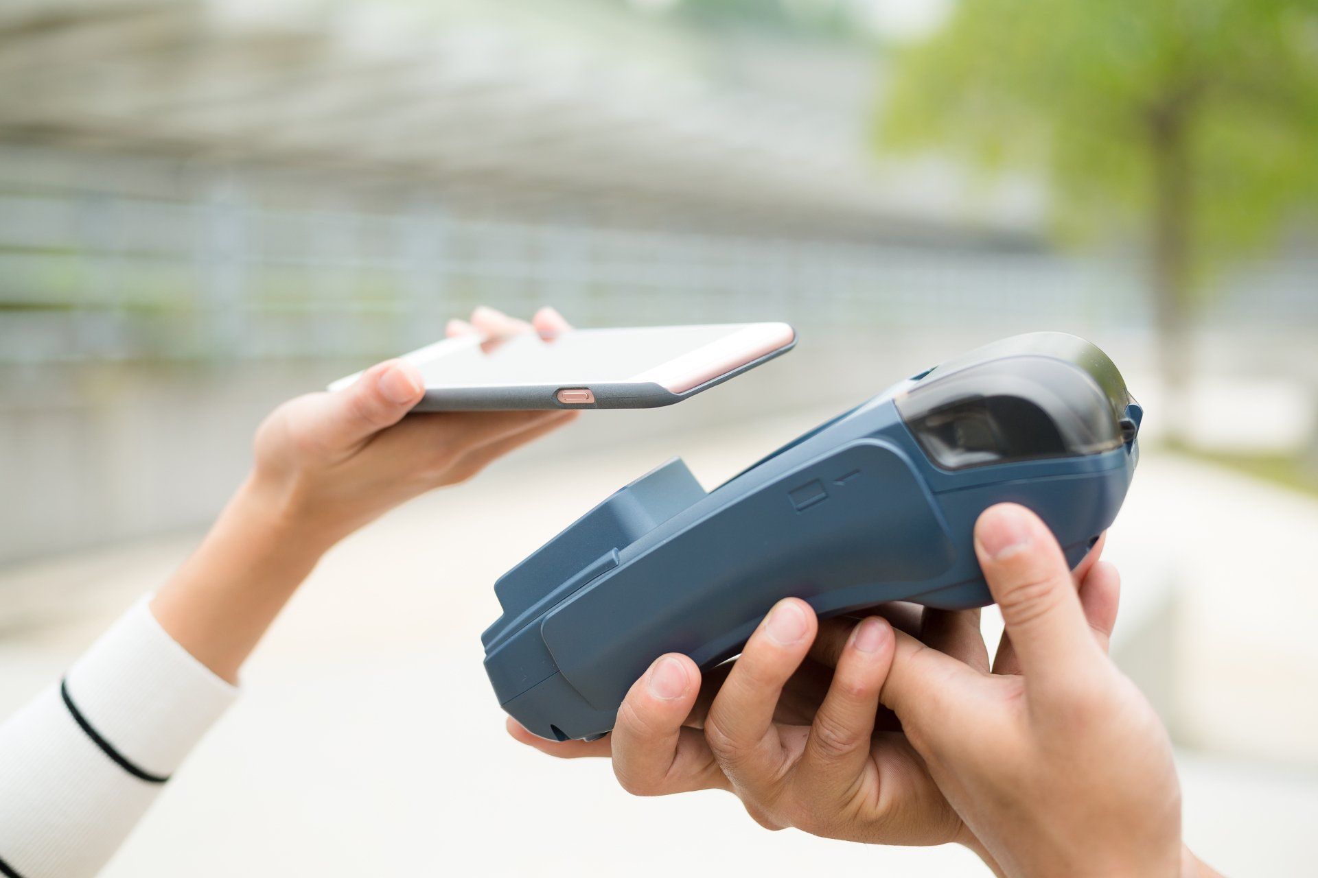 Una persona está utilizando un teléfono inteligente para pagar con una máquina de tarjetas de crédito.