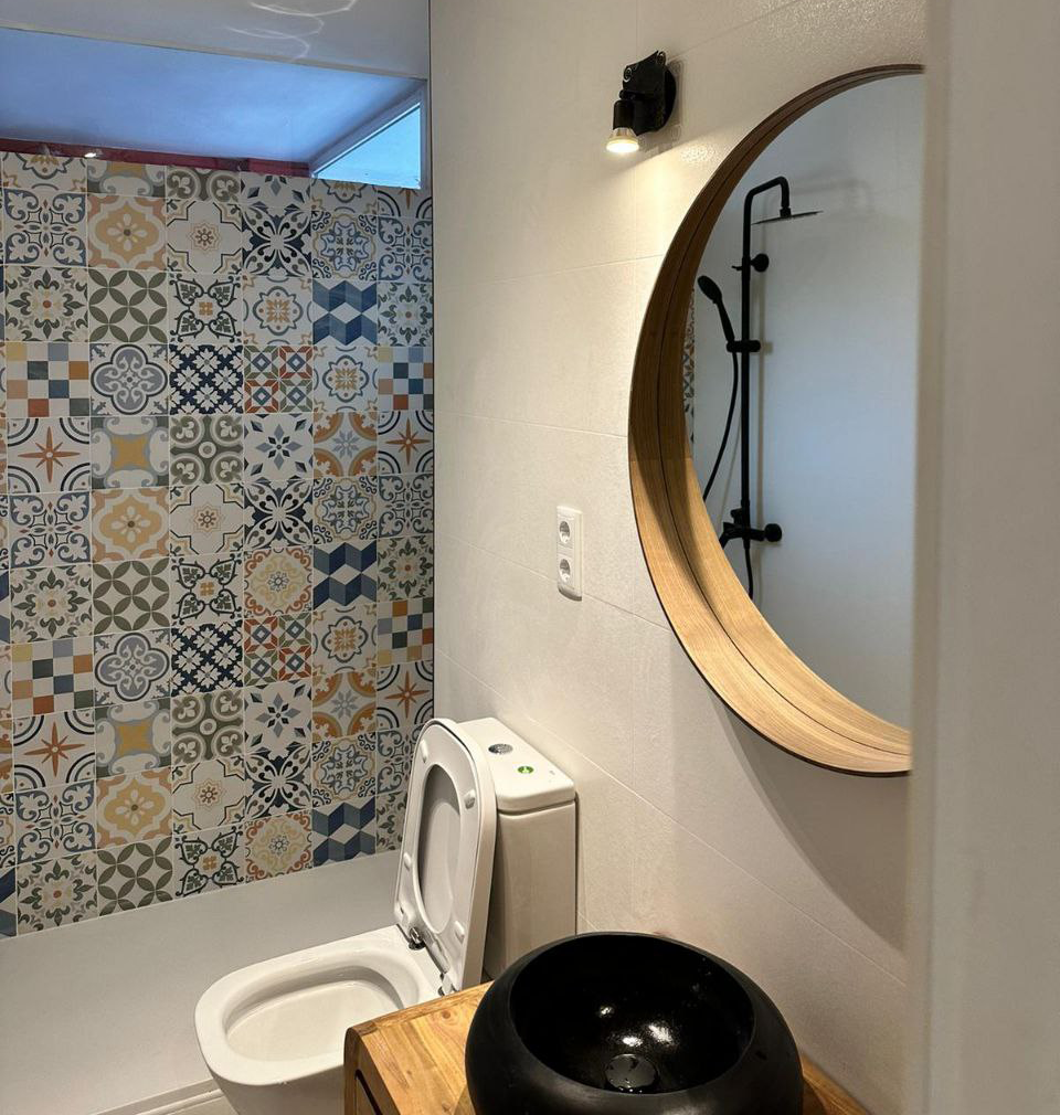 Un cuarto de baño con inodoro, lavabo, espejo y ducha.