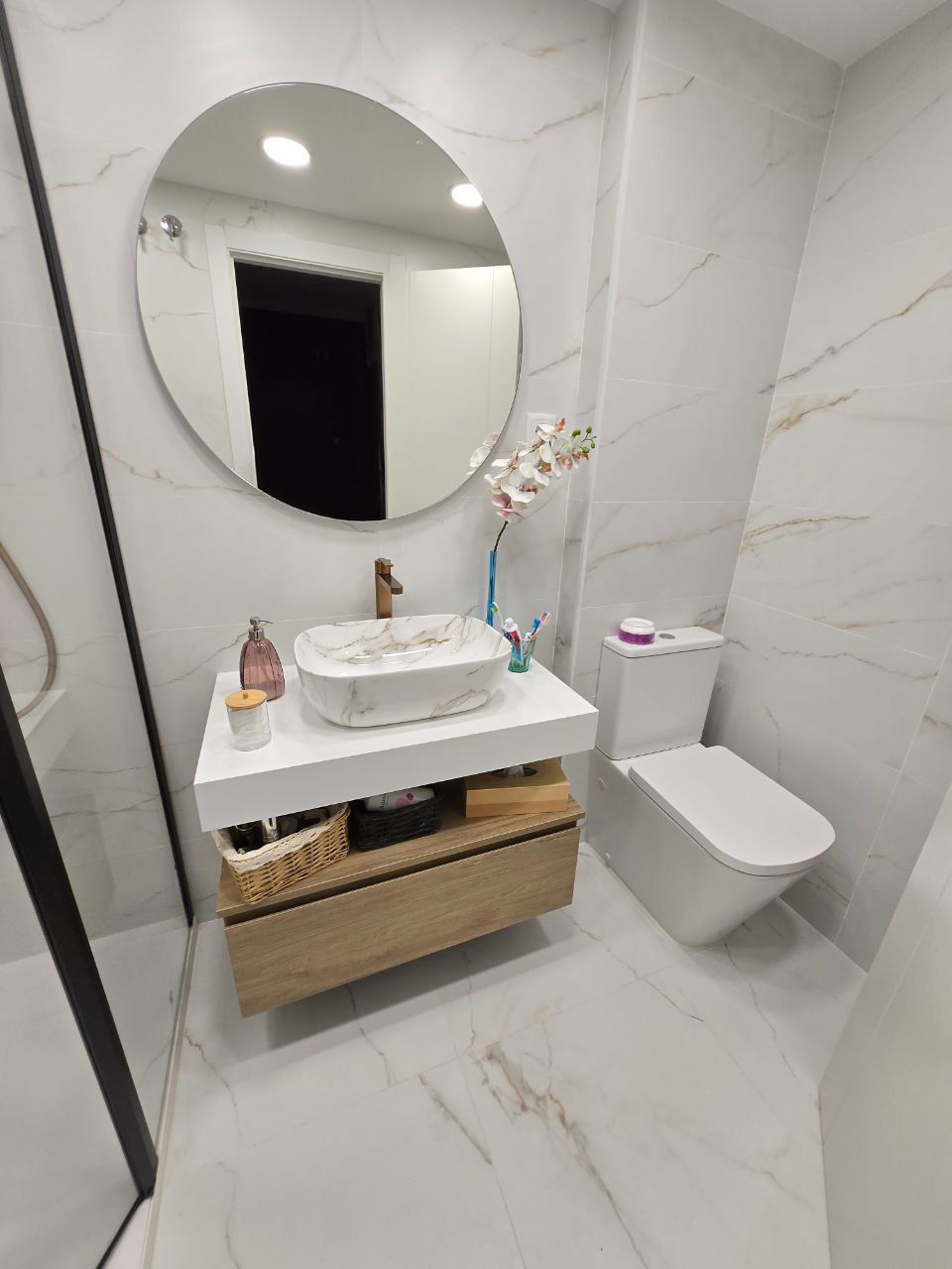 Un cuarto de baño con inodoro, lavabo, espejo y ducha.
