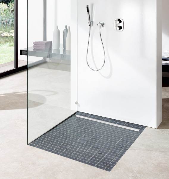 Una ducha con puerta de cristal y suelo de baldosas.