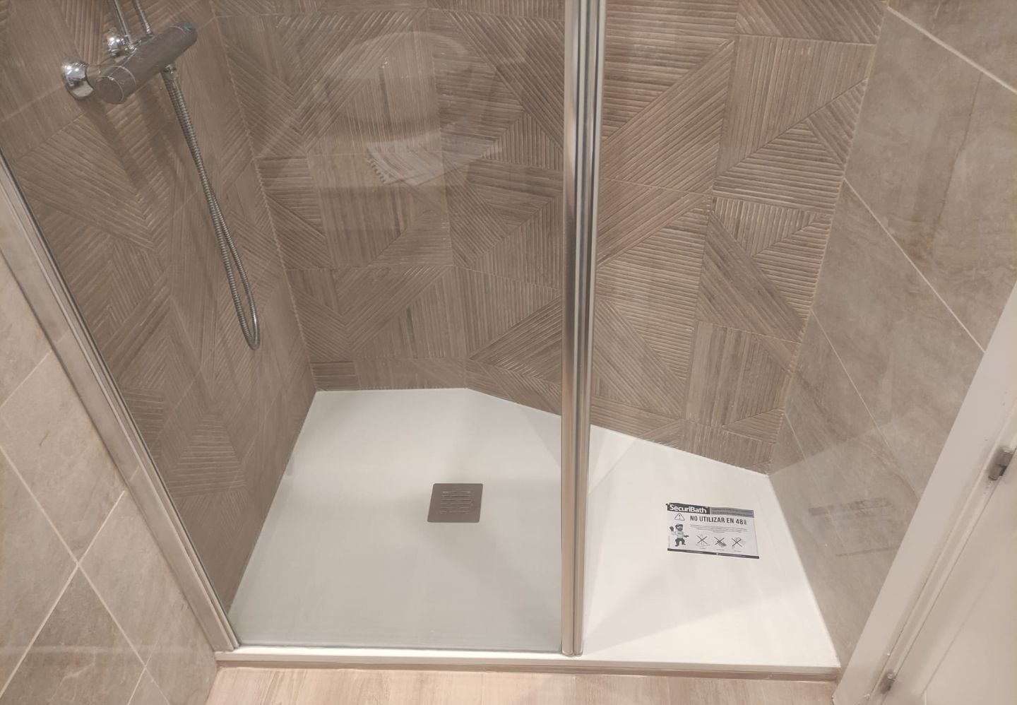 Un baño con plato de ducha con puerta de cristal.
