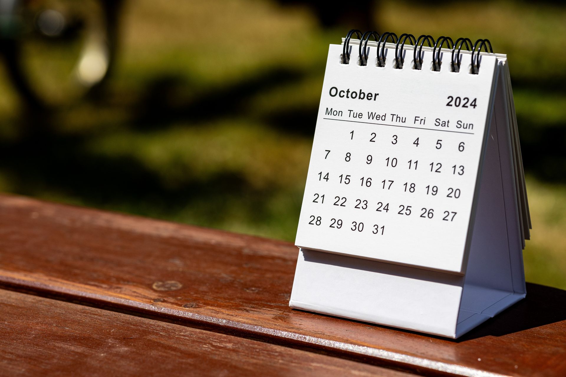 A calendar for october is sitting on a wooden bench.