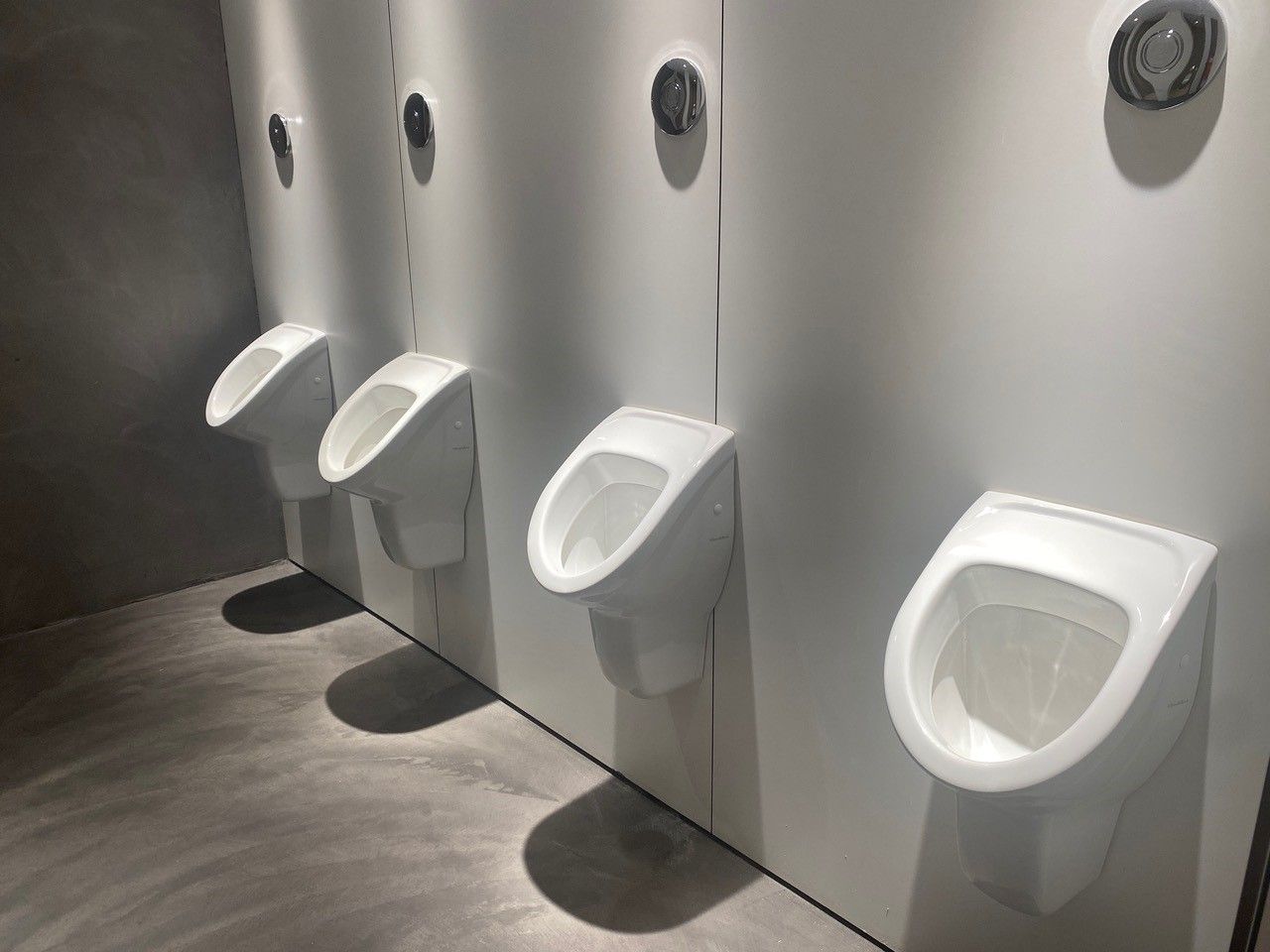 Una fila de urinarios blancos en un baño público.