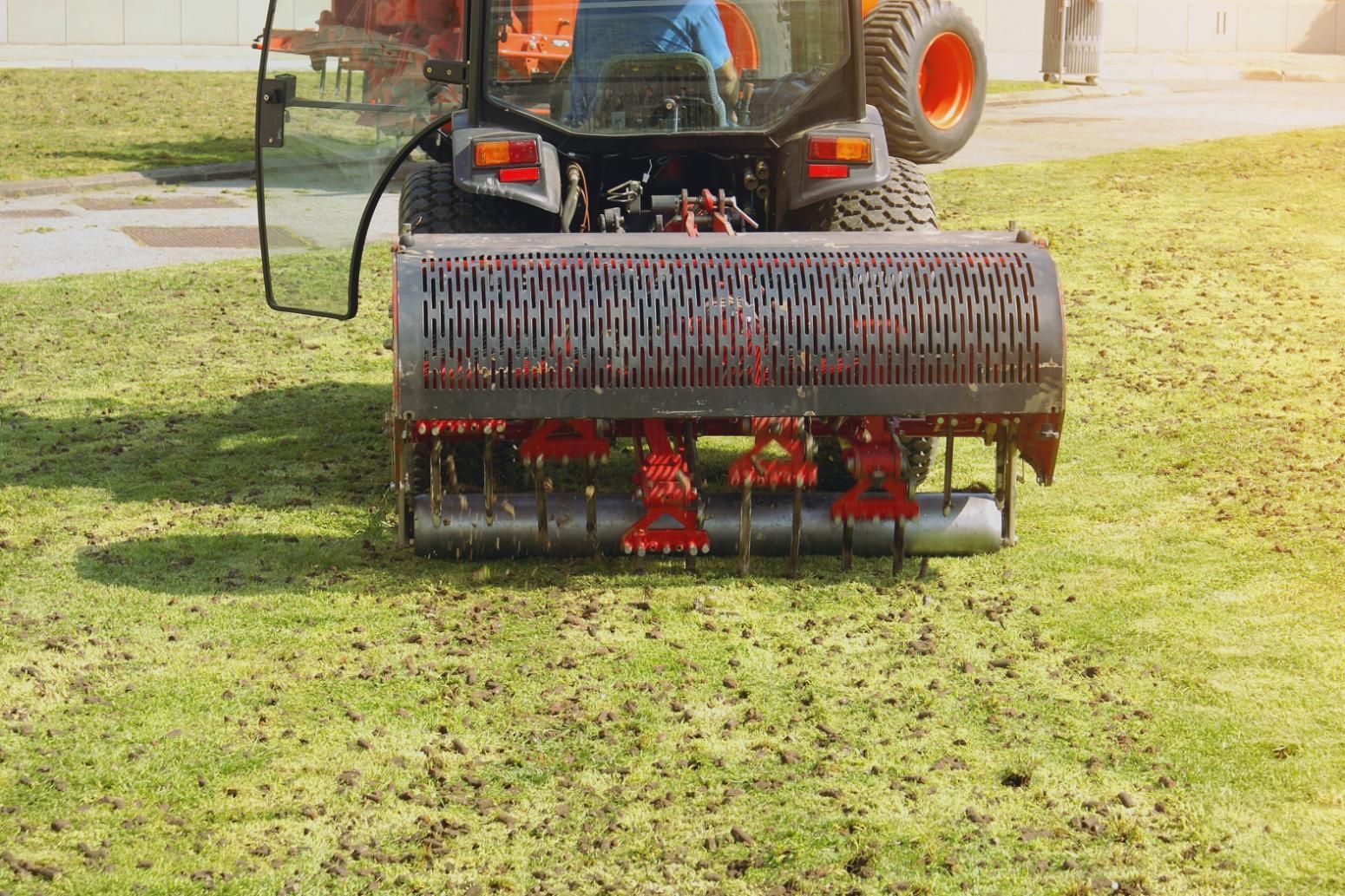 Tractor with an aerator attachment on a green lawn, aerating the grass.