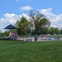 There is a playground in the middle of a grassy field.