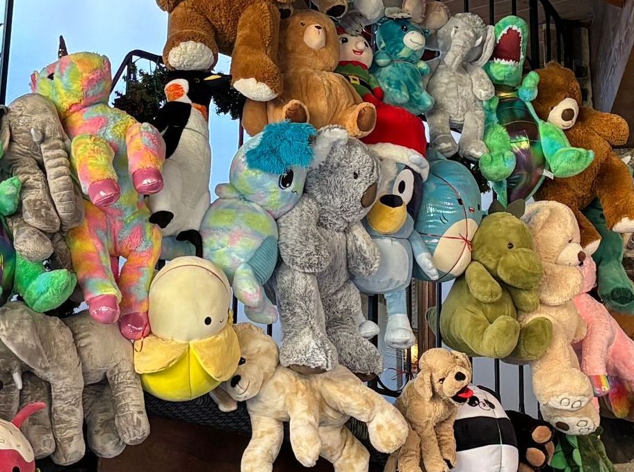 A bunch of stuffed animals hanging on a railing.