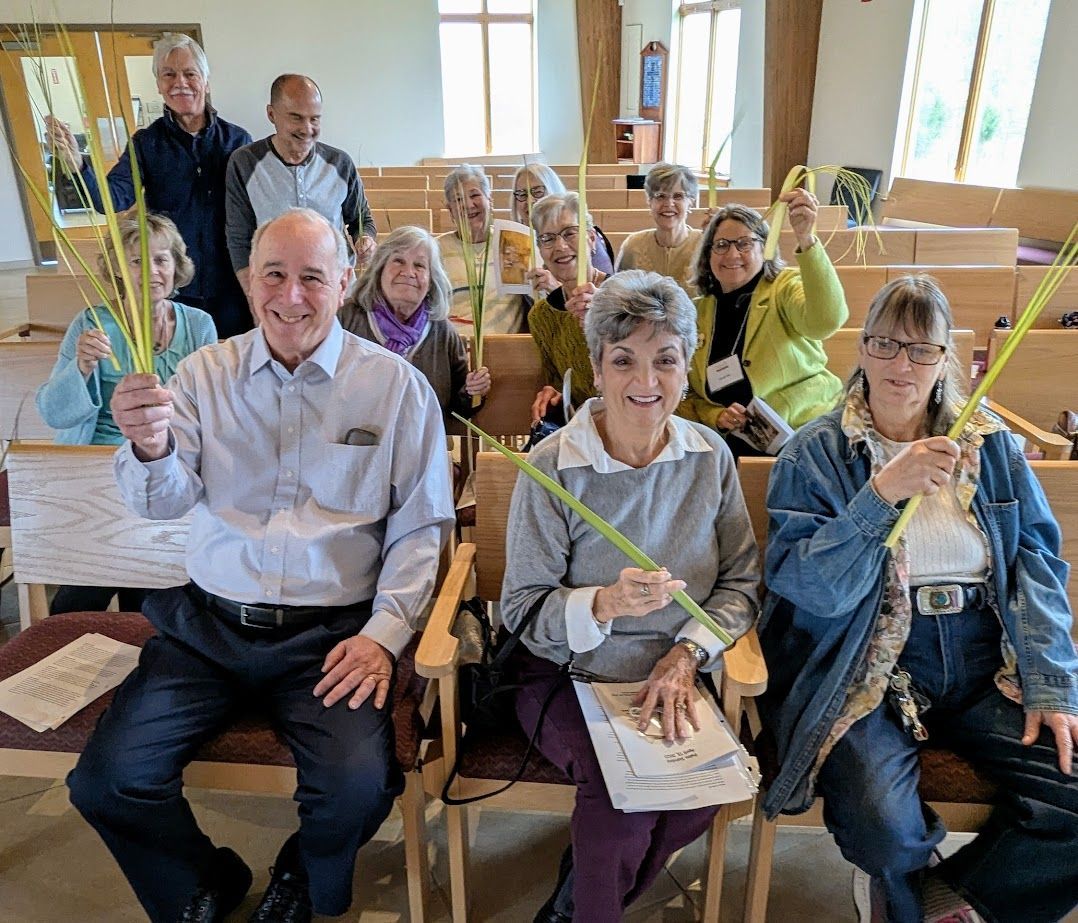 A group of people are sitting in a church holding palm branches.