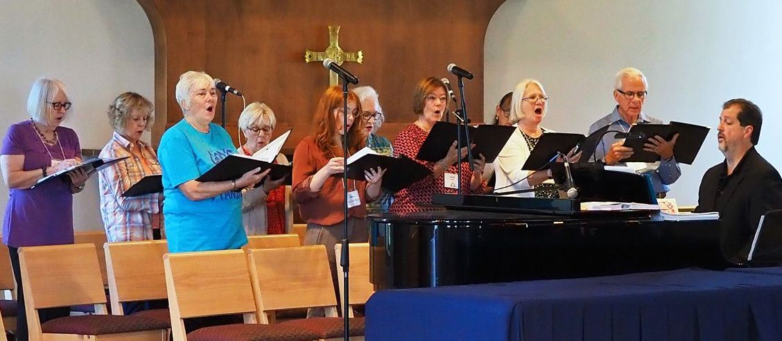 A group of people are singing in a church while a man plays a piano.