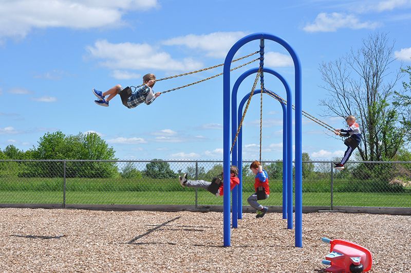 A group of children are playing on swings at a playground.