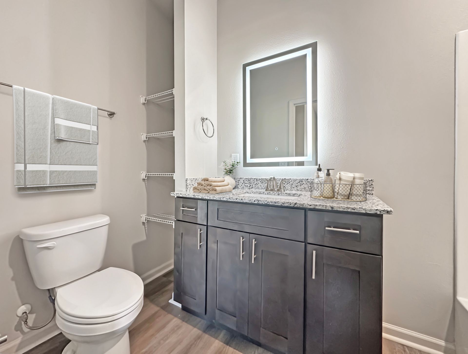 Modern bathroom with dark vanity, white toilet, mirror, and tiled shower area