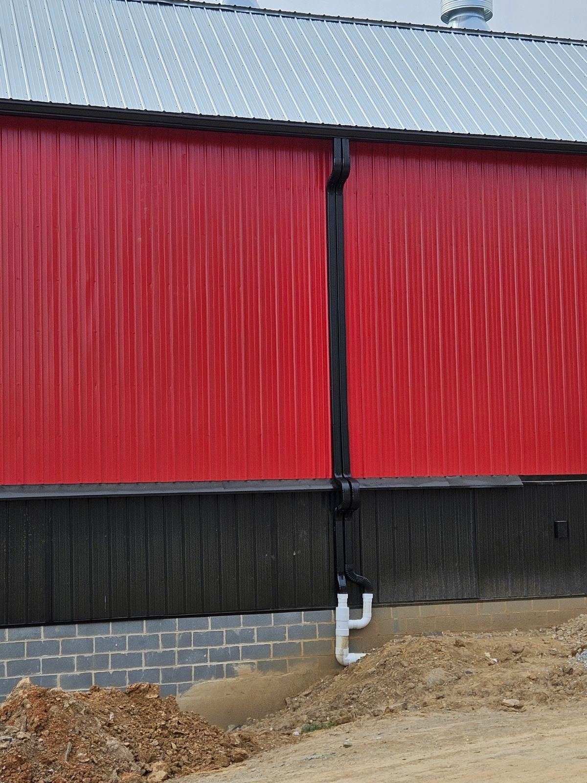 A red barn with a black gutter on the side