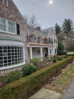 A Large Brick House With A Porch And A Hedge In Front Of It — Lititz, PA — Trailside Spouting, LLC