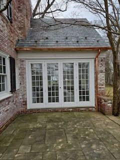 A Brick House With A Large Window And A Patio In Front Of It — Lititz, PA — Trailside Spouting, LLC