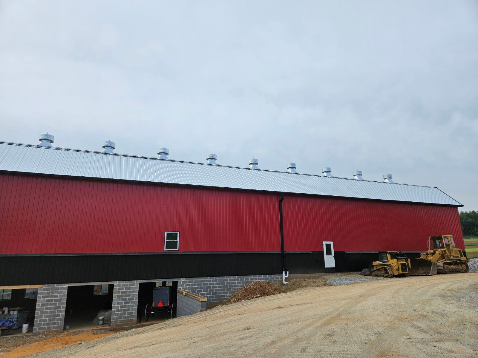 A large red barn with a white roof is sitting on top of a dirt field.